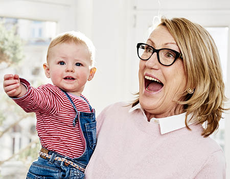 Femme senior avec des verres progressifs portant son petit-fils dans les bras